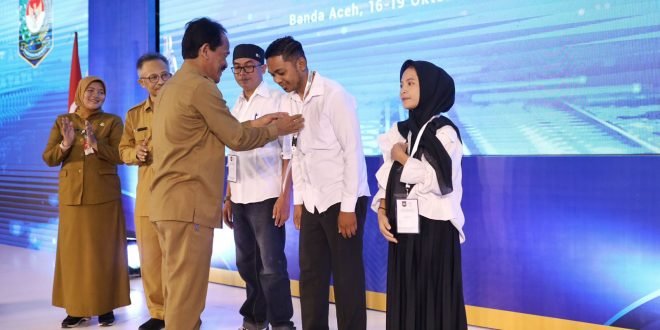 Asisten Perekonomian dan Pembangunan Sekda Aceh, Ir. Mawardi, bersama Dirjen Bina Pemerintahan Desa, Dr. Eko Prasentyanto Purnomo Putro, S.Si, M.Si, MA, menyematkan tanda peserta pada kegiatan Peningkatan Kapasitas Aparatur Pemerintah Desa dan Pengurus Kelembagaan Desa di Hotel Grand Nanggroe, Banda Aceh, Selasa (17/10/2023).