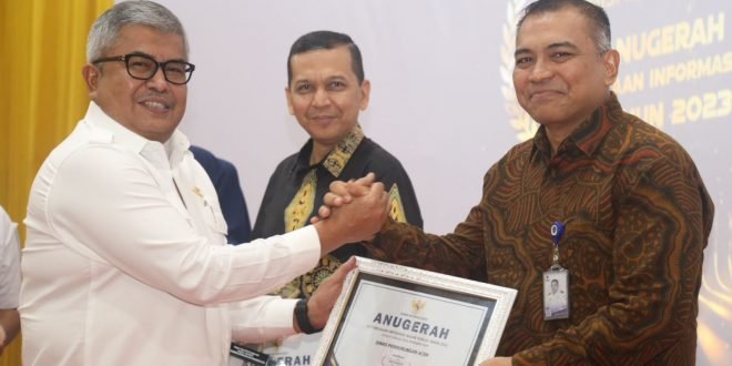 Sekda Aceh, Bustami SE, M.Si, saat menyerahkan penghargaan kepada pemenang Anugerah Keterbukaan Informasi Publik Tahun 2023 yang diselenggarakan Komisi Informasi Aceh di Aula Amel Convention Hall, Banda Aceh, Rabu (6/12/2023).