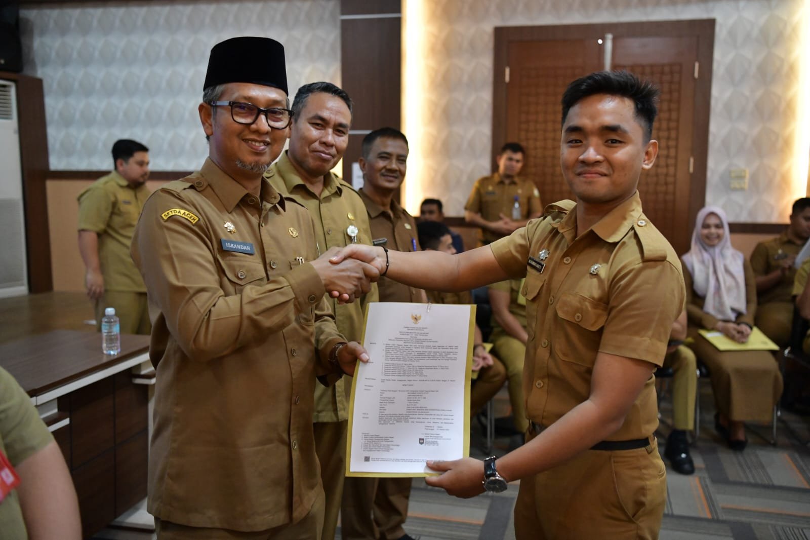 Asisten Administrasi Umum Sekda Aceh, Dr. Iskandar AP didampingi Kepala Badan Kepegawaian Aceh, Abdul Qohar dan Kepala Biro Organisasi Setda Aceh, Daniel Arca Menyerahkan Dokumen Kepegawaian Dalam Rangka Penepatan Tugas Lulusan IPDN Provinsi Aceh Angkatan XXIX di Aula Badan Kepegawaian Aceh, Banda Aceh, Selasa (19/12/2023).