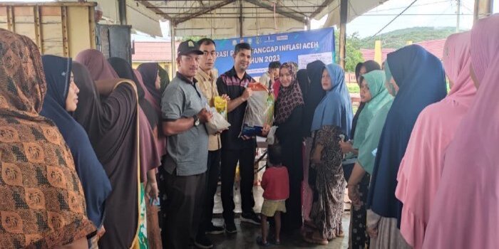 Plt KaDiskopukmdag Aceh Besar Trizna Darma, ST menyerahkan paket secara simbolis kepada pembeli di lokasi pasar murah dipasar Krueng Raya, Kecamatan Mesjid Raya, Aceh Besar, Sabtu (2/12/2023).