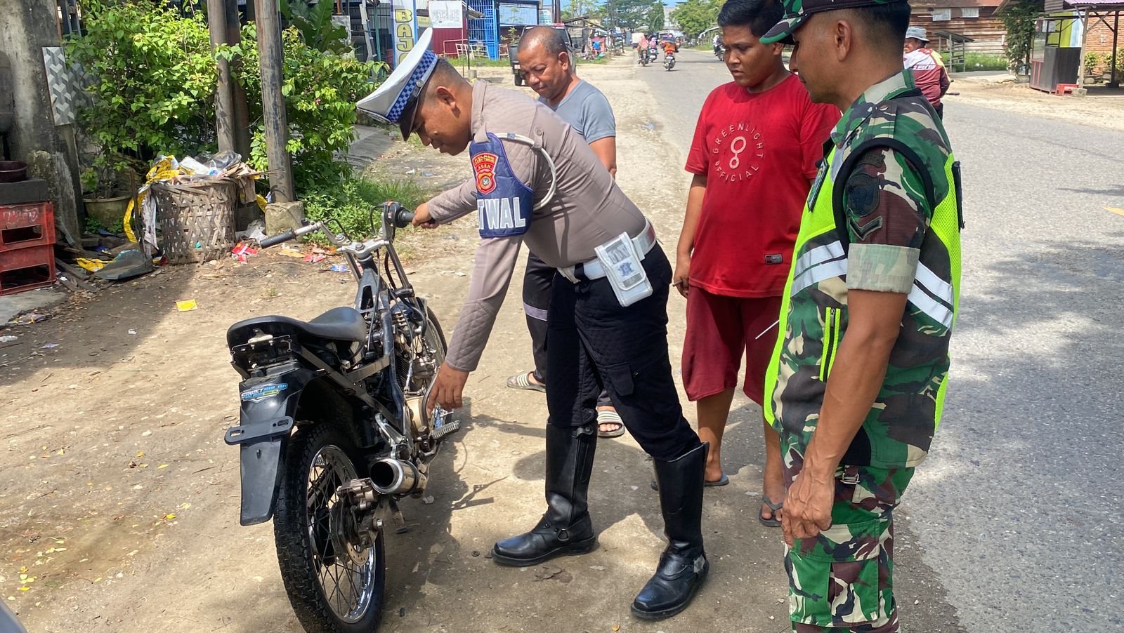 Salah seorang personel Satlantas mengamankan sepeda motor yang menggunakan knalpot brong di Aceh. Foto : Humas Polda Aceh