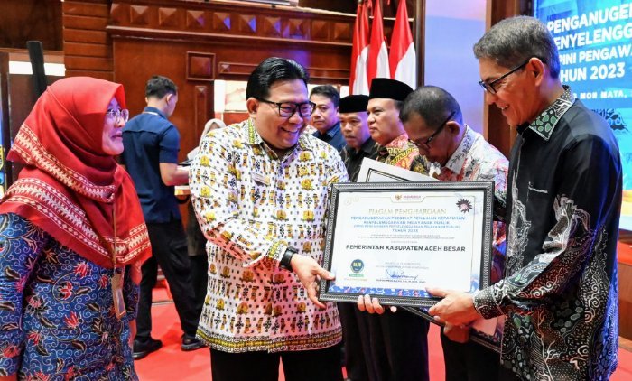Pimpinan Ombudsman RI, Dadan S. Suharmawijaya menyerahkan Piagam Penghargaan dan Sertidikat Penganugerahan Predikat Penilaian Kepatuhan Penyelenggaraan Pelayanan Publik kepada Asisten III Pemkab Aceh Besar, Jamaluddin, S.Sos, MM.